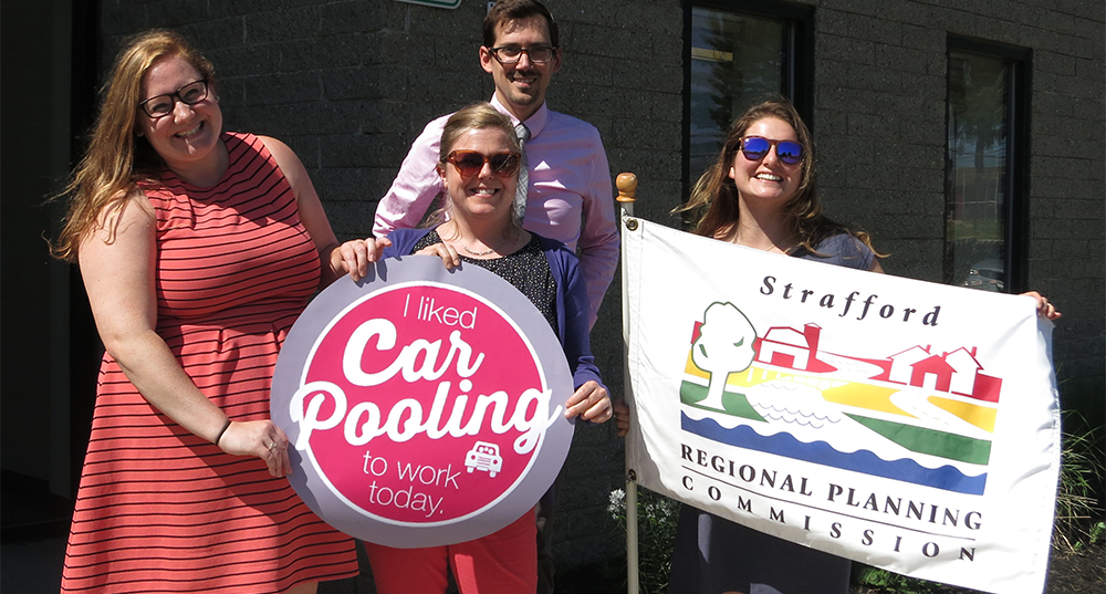 SRPC staff pose with the SRPC flag and a sign saying I liked carpooling to work today