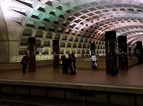Photo from within a Metro tunnel in D.C. with green and purple lights reflected on the ceiling