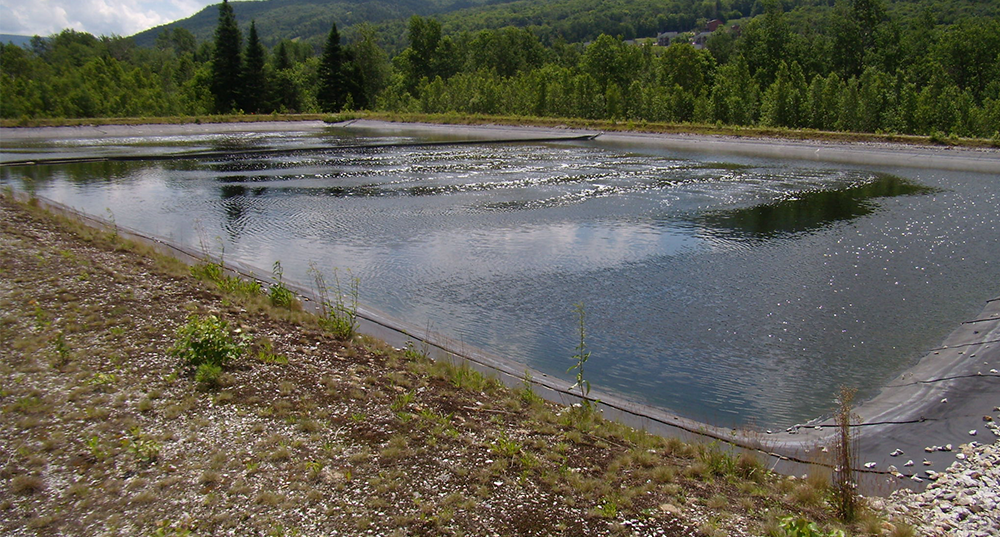 Wastewater lagoon surrounded by grass and trees