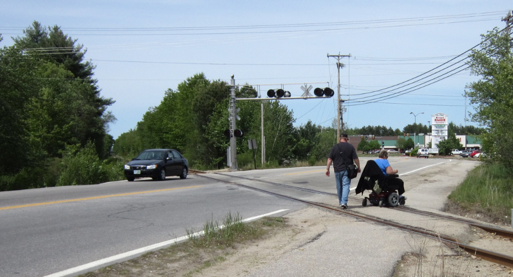 Wheelchair user and pedestrian crossing railroad tracks on NH125 in Rochester